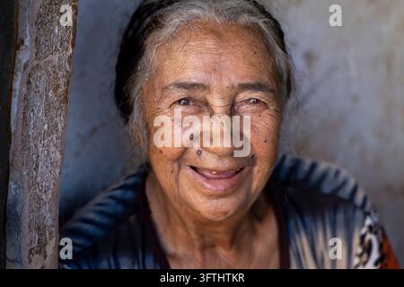 Ancienne femme souriant chaleureusement debout dans un encadrement de porte, Vakinankaratra, Antsirabe, Madagascar Banque D'Images