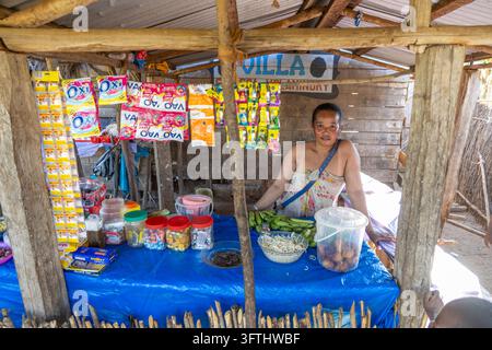 Femme vendant des bananes et des articles ménagers à un petit stand de bord de route, Menabe, Tsiribihina, Madagascar Banque D'Images