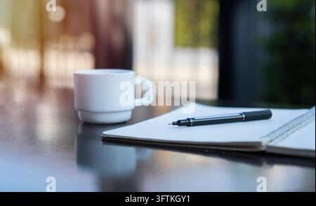Planification, affaires, travail de bureau, papeterie ou un concept éducatif. Vue latérale d'un cahier ouvert, d'un stylo et d'une tasse de thé sur la table noire à ou Banque D'Images