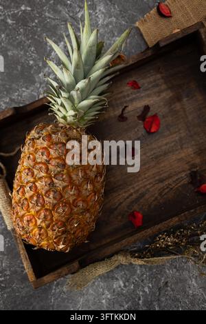 Image verticale d'ananas sur un plateau en bois sur un fond rustique, fruit tropical parfumé et sucré. nourriture sombre Banque D'Images