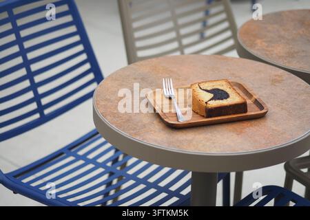 En-cas sur une assiette en bois à une table de café avec des chaises bleues Banque D'Images