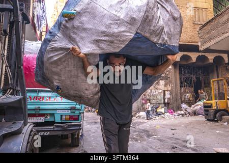 À Moqattam, Le Caire, un homme porte un énorme sac de déchets recyclables sur son dos dans la rue. Banque D'Images