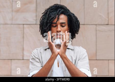 Jeune homme tenant une boule de cristal, les yeux fermés, méditant et se concentrant sur le futur Banque D'Images