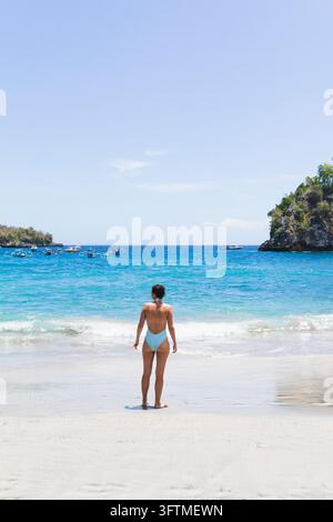 Femme en maillot de bain debout sur une plage tropicale Banque D'Images