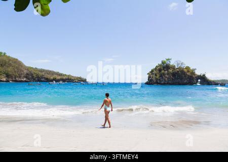 Femme en maillot de bain marchant sur une belle plage tropicale Banque D'Images