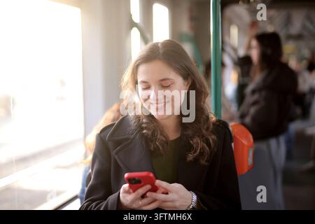 Femme heureuse utilisant son téléphone dans les transports en commun Banque D'Images