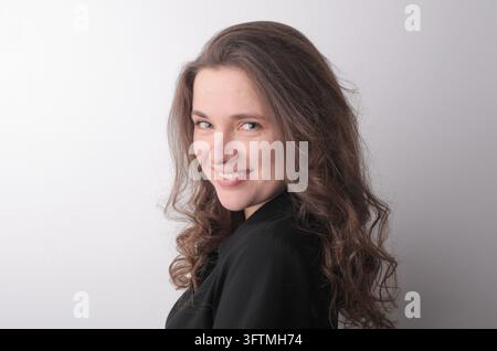 Belle femme caucasienne souriant par-dessus son épaule Banque D'Images