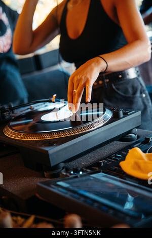 DJ féminine touchant un vinyle en rotation sur une platine lors d'un set en direct Banque D'Images