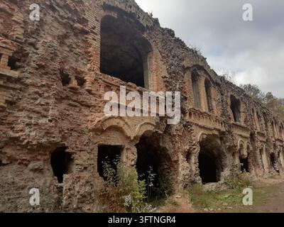 Long bâtiment en maçonnerie en ruine avec des ouvertures en arc vides et des murs rugueux Banque D'Images