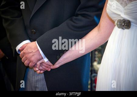 Les mariés se tiennent la main lors de leur cérémonie de mariage solennelle à Séville, Andalousie, Espagne. Un moment symbolique d'union et d'engagement. Banque D'Images