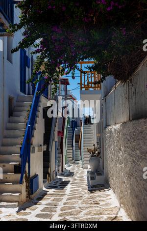 Une ruelle pavée de pierre étroite dans Mykonos Town présente des bâtiments blanchis à la chaux, des balcons colorés, des bougainvillées en fleurs et une architecture cycladique traditionnelle Banque D'Images