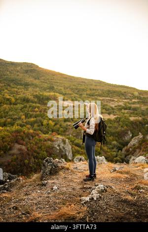Jeune femme en randonnée dans les montagnes tenant des jumelles et contemplant la vue Banque D'Images