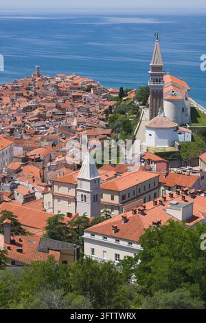 Vue élevée de la péninsule de Piran avec des toits orange, le clocher de l'église Saint-Georges et la mer Adriatique. Banque D'Images