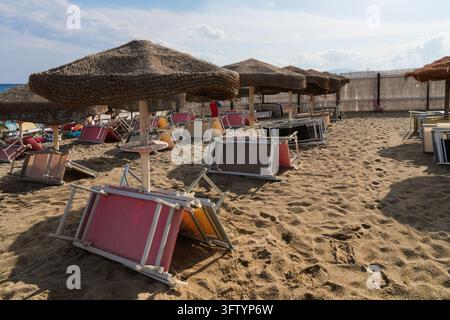 Transats pliés et parasols en paille sur une plage de sable déserte à la fin de la saison, Calabre, Italie Banque D'Images