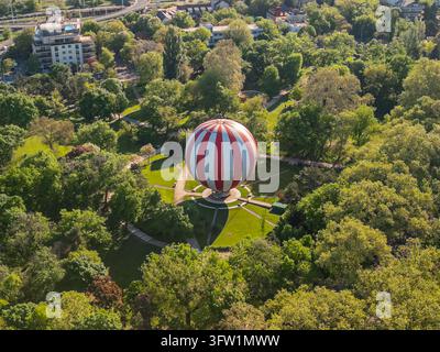 Photo aérienne par drone en gros plan du FlyBalloon dans le Parc de la Ville de Budapest, centré parmi les arbres, avec le Private Rooftop visible au loin à l'arrière-plan Banque D'Images