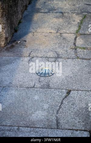 Coquille en métal incrustée dans un pavé marquant le chemin de Saint-Jacques-de-Compostelle. Banque D'Images