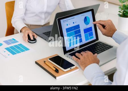 Gros plan de collègues analysant un tableau de bord commercial sur l'écran d'un ordinateur portable Banque D'Images