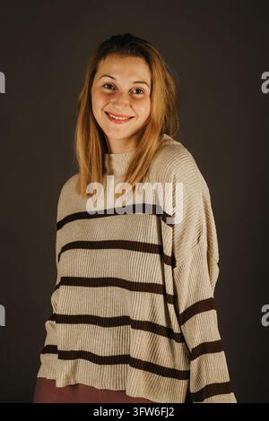 Jeune femme modèle un pull rayé dans un studio Banque D'Images