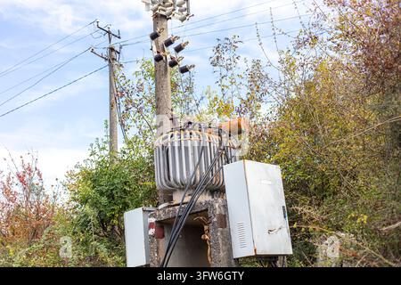 Albanie, Bajza : Vue en contre-plongée d'un ancien transformateur électrique monté sur un poteau en béton avec des câbles, en plein air. Banque D'Images