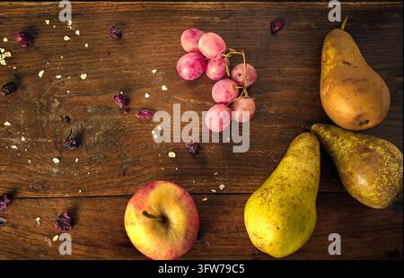 Nature morte de récolte automnale fraîche avec raisins rouges, poires mûres, prune et bol en céramique sur fond en bois vintage. Espace de copie pour concept d'aliments saisonniers. Banque D'Images