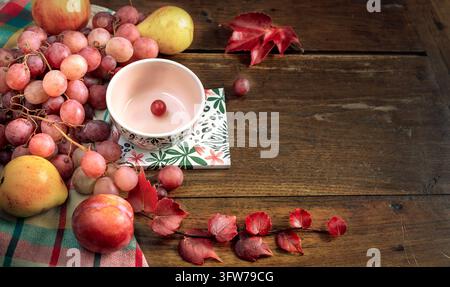 Nature morte de récolte automnale fraîche avec raisins rouges, poires mûres, prune et bol en céramique sur fond en bois vintage. Espace de copie pour concept d'aliments saisonniers. Banque D'Images