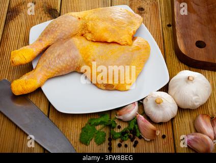 Cuisses de poulet crues sur planche à découper et assiette en gros plan Banque D'Images