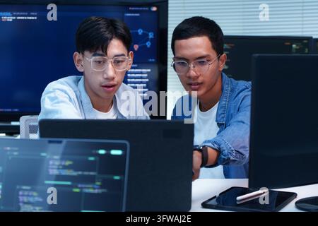 Deux développeurs logiciels collaborent sur la programmation numérique, analysent le code et développent des solutions technologiques innovantes en IA. Banque D'Images