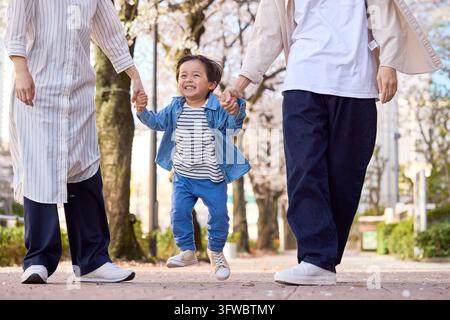 Parent et enfant japonais marchant main dans la main avec le sourire aux lèvres Banque D'Images