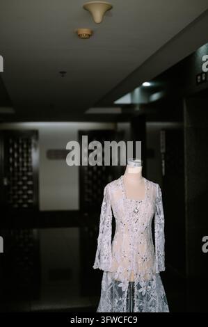 Une robe de mariée élégante en dentelle blanche exposée sur un mannequin dans un couloir intérieur moderne. Banque D'Images