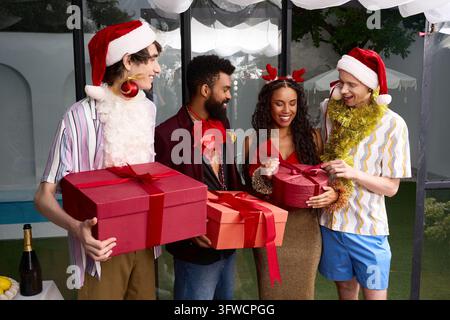 Quatre amis échangent des cadeaux rouges en plein air lors d'une réunion festive du Nouvel An. Banque D'Images