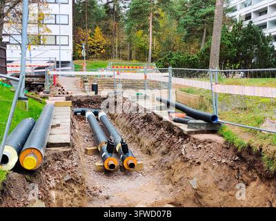 Une tranchée de construction ouverte en Finlande pendant l'automne, montrant la réparation et l'entretien de l'infrastructure de chauffage urbain souterraine avec une nouvelle isolation Banque D'Images