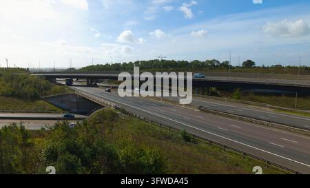 Vue aérienne de l'échangeur de Catthorpe montrant une bretelle d'autoroute animée avec des véhicules sur la route à plusieurs voies entourée de talus verts, Lutterworth Banque D'Images