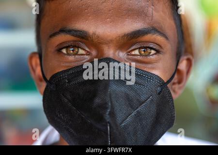 Portrait d'un jeune homme aux yeux verts portant un masque facial noir à Ruwanwelisaya, Province du Centre-Nord, Anuradhapura, Sri Lanka Banque D'Images