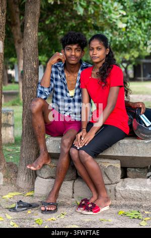 Jeune homme et jeune femme assis ensemble sur un mur de pierre sous des arbres, Province du Nord, Jaffna, Sri Lanka Banque D'Images