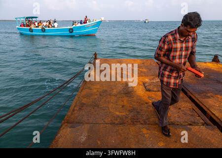 Homme marchant sur une rampe de ferry rouillée alors qu'un bateau de passagers bondé arrive, Province du Nord, île de Delft, Sri Lanka Banque D'Images