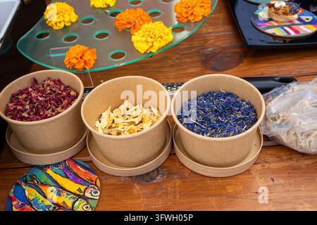 Assortiment de pétales comestibles séchés comprenant la bleu cyan Centaurea cyanus et les soucis frais Tagetes, présentés dans des bols en papier sur une table en bois pour gou Banque D'Images
