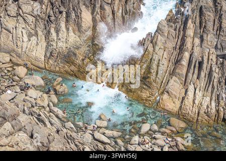 Vue aérienne de personnes nageant dans les eaux turquoise du Spa naturel d'Injidup, entourées de formations rocheuses abruptes et de vagues déferlantes à Yallingu Banque D'Images