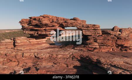Vue aérienne de Nature's Window, un arc de grès érodé par le vent avec des formations rocheuses stratifiées et une vallée fluviale en arrière-plan, Parc national de Kalbarri Banque D'Images