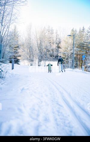 Un père aide son tout-petit à apprendre le ski de fond sur un sentier enneigé dans la région d'Helsinki, en Finlande, lors d'une sortie familiale active en hiver. Banque D'Images