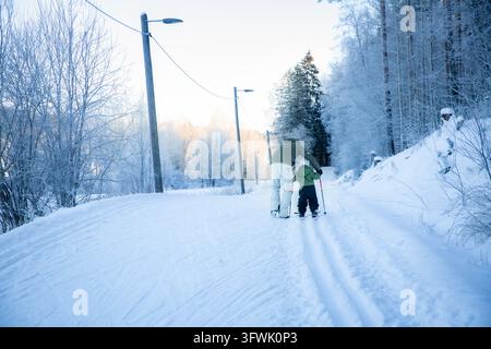 Un père aide son tout-petit à apprendre le ski de fond sur un sentier enneigé dans la région d'Helsinki, en Finlande, lors d'une sortie familiale active en hiver. Banque D'Images