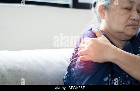 Concept de santé, femme asiatique âgée souffrant de douleurs à l'épaule droite, femme utilisant sa main gauche pour tenir son épaule droite en raison de douleurs à l'épaule Banque D'Images
