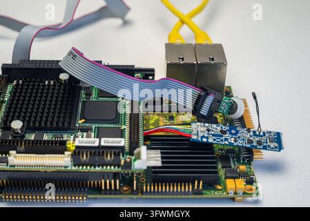 Une personne connecte des fils à des appareils domestiques intelligents sur une table dans un espace de travail bien éclairé. L'installation comprend des circuits et des câbles. Banque D'Images
