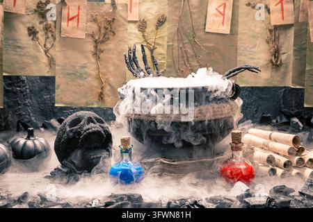 Configuration de laboratoire de sorcière effrayante avec un chaudron fumant rempli de potion magique, des mains de squelette, des potions magiques dans des bouteilles en verre et des parchemins anciens. Banque D'Images