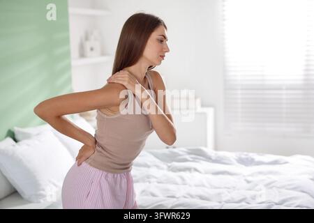 Femme souffrant de douleurs au dos sur le lit à la maison. Espace pour texte Banque D'Images