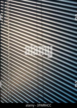 Lumière du soleil abstraite et ombres diagonales des stores sur une surface texturée Banque D'Images