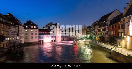 Des maisons colorées illuminées et des façades en bois à encorbellement se reflètent dans la rivière au crépuscule à la Petite France, Strasbourg, Alsace, France. Banque D'Images