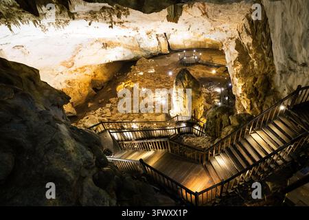 Escaliers et passerelles en bois illuminés à l'intérieur d'une grotte de calcaire à Phong Nha, Vietnam. Banque D'Images