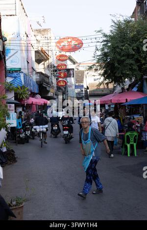 Chiang Mai, Thaïlande - 17 janvier 2026 : Une rue animée de Chiang Mai, en Thaïlande, où des piétons marchent parmi des motos sous des couleurs vives… Banque D'Images
