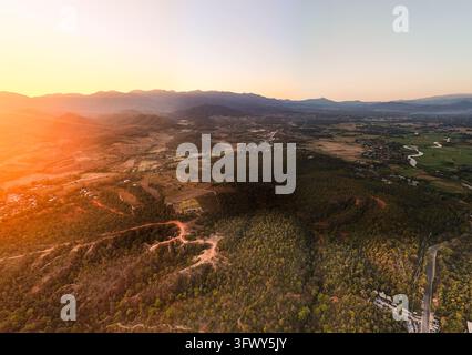 Pai, Thaïlande - 21 janvier 2026 : Une vue aérienne capture des collines ondulantes, des forêts denses et des hameaux dispersés baignés dans la lueur chaude d'un... Banque D'Images