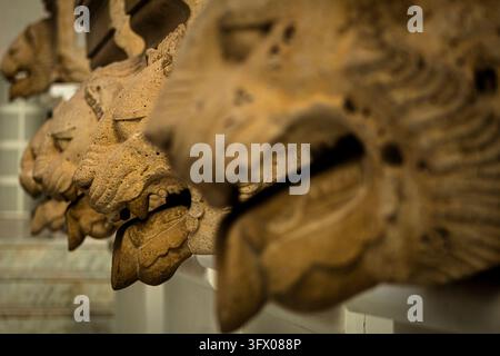 Gros plan de têtes de lion en pierre sculptées avec des textures érodées et des détails complexes, mettant en valeur l'artisanat traditionnel et les ornements architecturaux historiques Banque D'Images